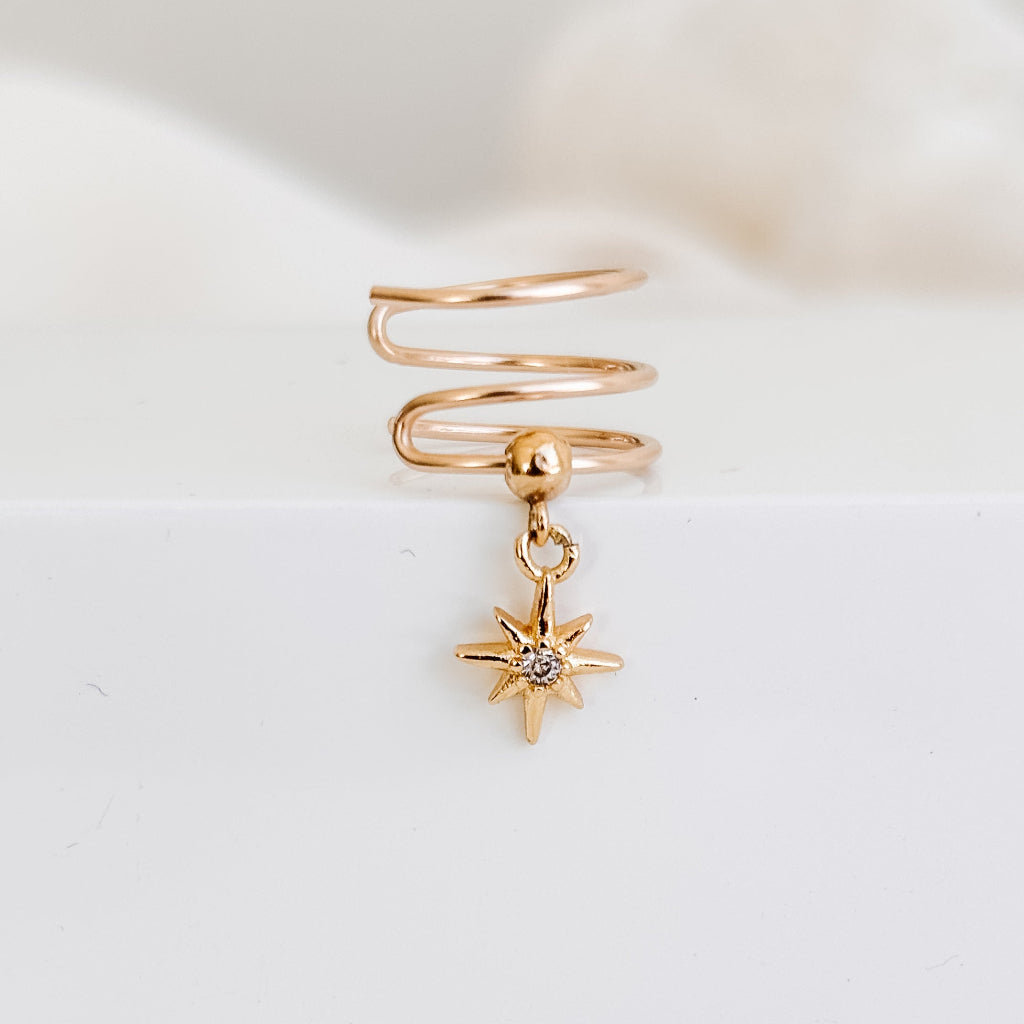 a triple line gold wire faux piercing ear cuff featuring a petite dangling cz north star charm.
