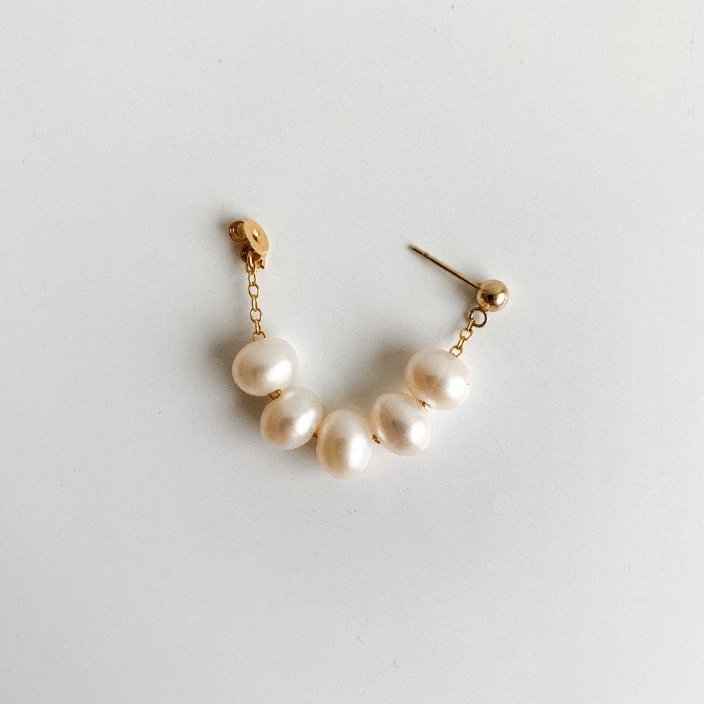 a single baroque pearl earring showing the front back design . Five oval-shaped pearls are strung on delicate chain and forms a hoop when the gold ball stud earring post is pushed into the butterfly nut.