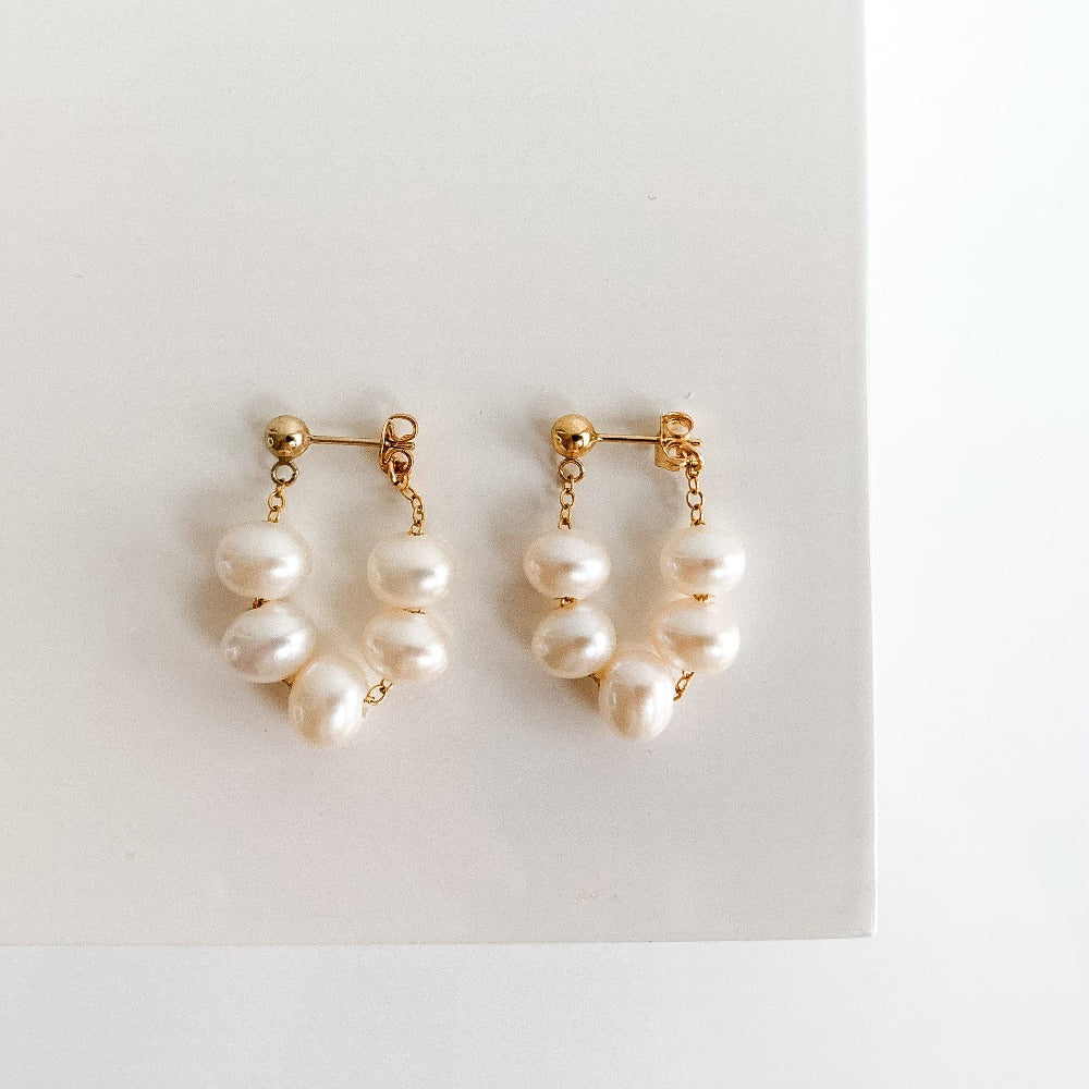 dainty freshwater pearl earrings featuring 5 oval luminous pearls threaded on chain forming a wrap around hoop when attached to the lobe.