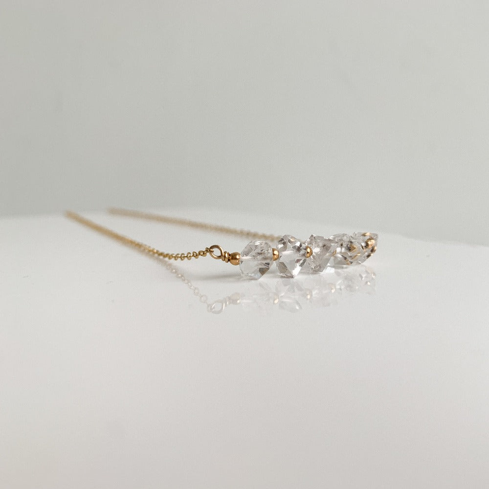 A gemstone pendant necklace featuring 5 raw crystal Herkimer Diamond stones alternating with tiny gold ball beads and set in delicate chain.
