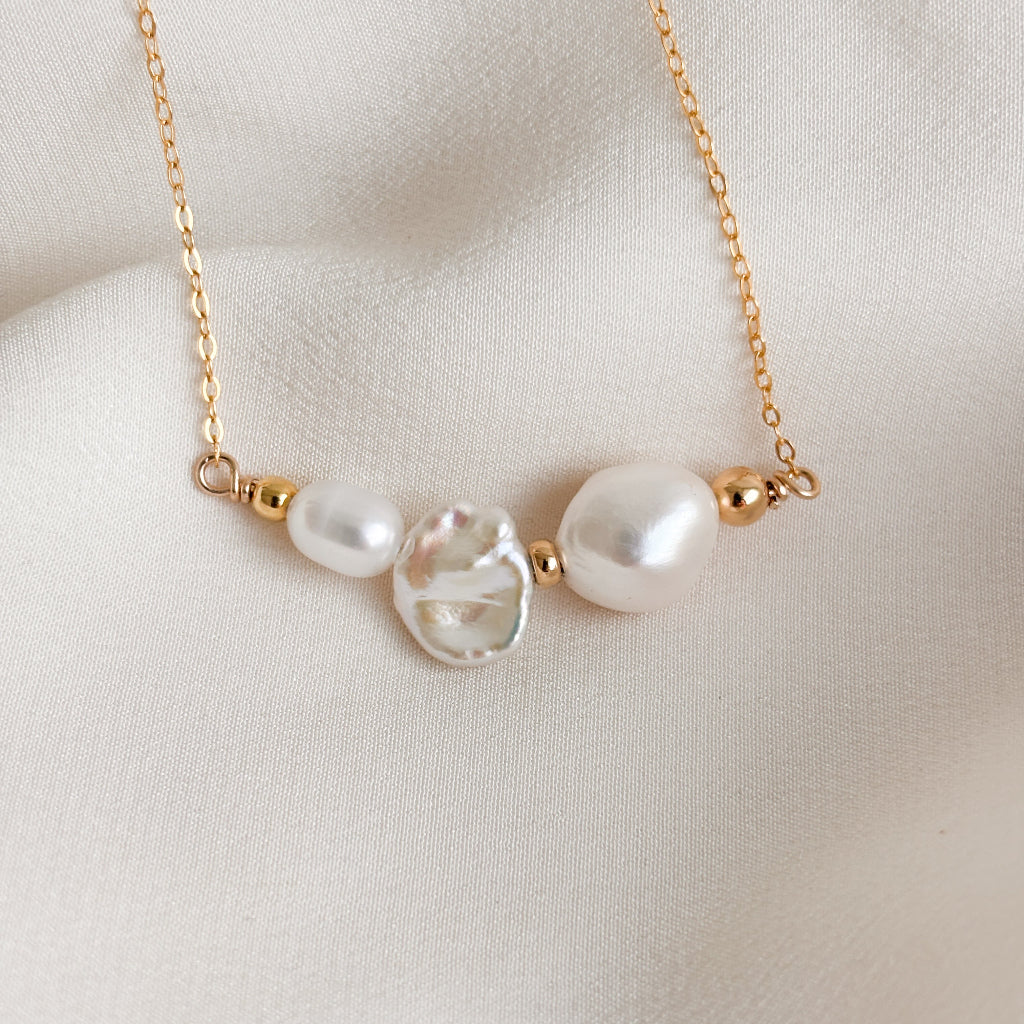 a dainty and unique gold pearl necklace featuring a trio of baroque pearls in different shapes; oval, biwa, and rice, accented with petite gold beads and set into the chain.