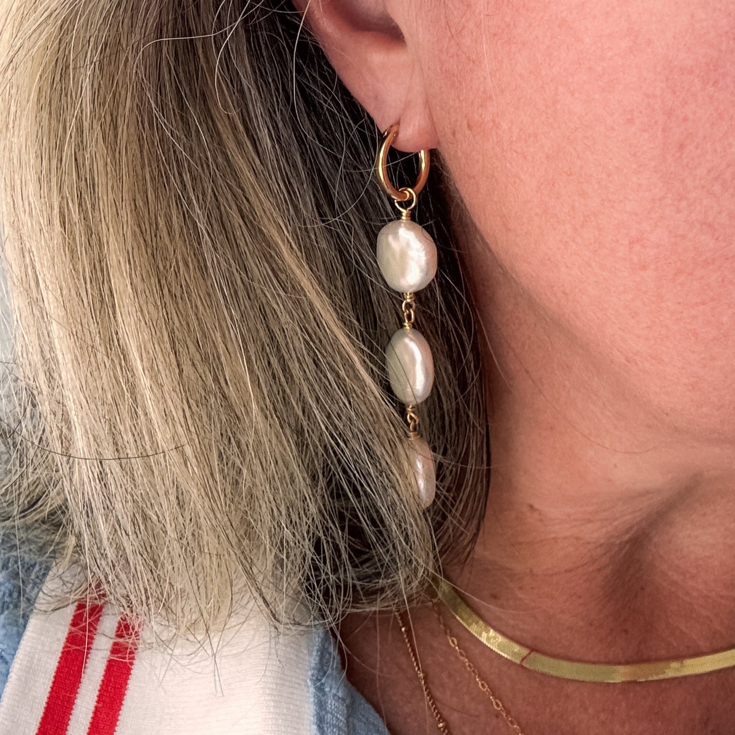 Close-up of a person wearing pearl earrings with a blurred background
