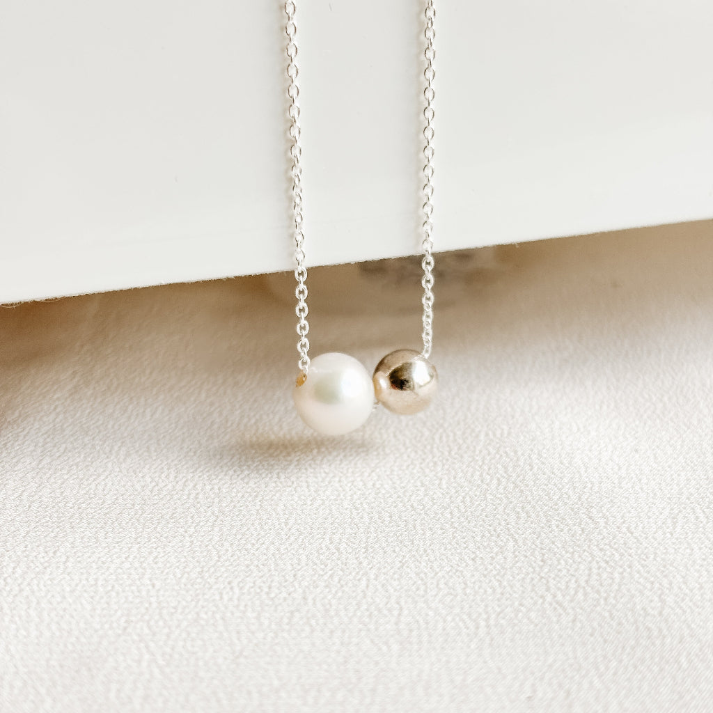 Necklace with a freshwater pearl and a sterling silver ball bead on a white background