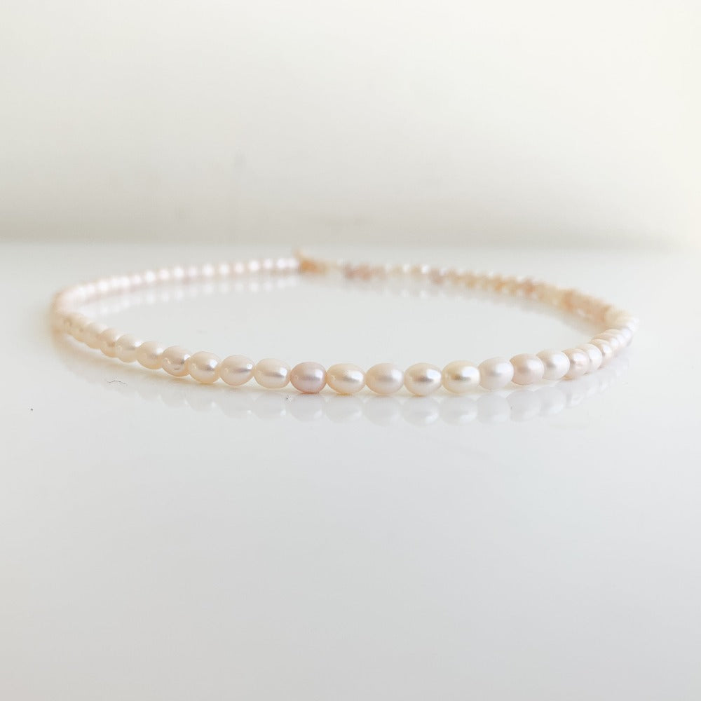 a classic pearl strand necklace featuring tiny oval-shaped freshwater pearls.