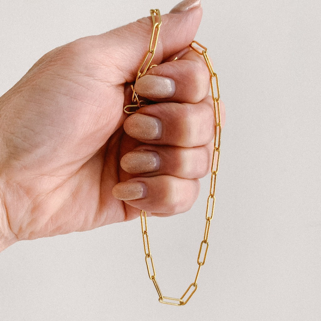 a large link paperclip chain necklace shown in hand . The necklace is crafted in 14k gold filled and has 3.8mm x 11mm links.