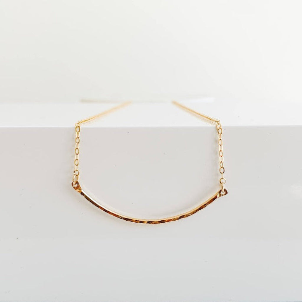 dainty 14k gold filled necklace featuring a textured curved bar pendant set into delicate chain.