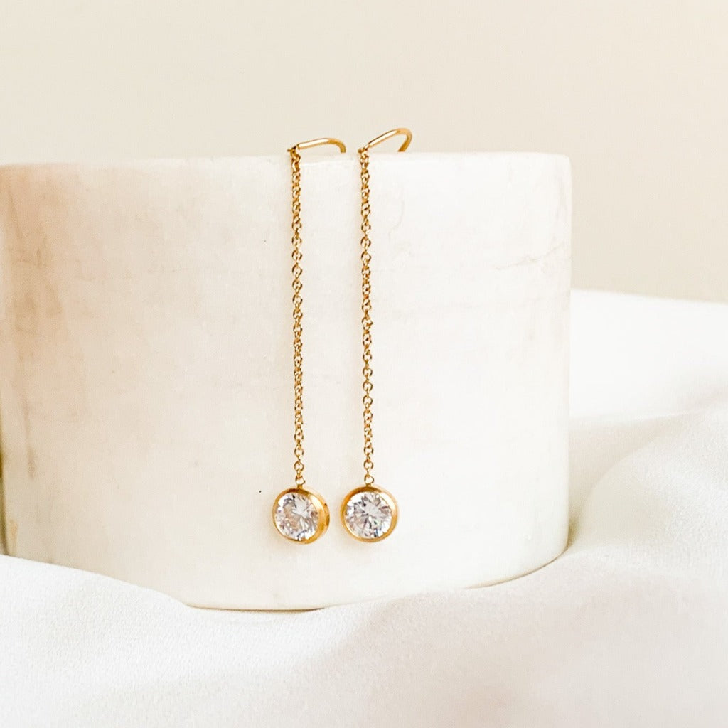 A pair of gold filled threader earrings with solitaire CZ drops. The threaders have a u-shaped cradle for extra security and are 3.5" long.