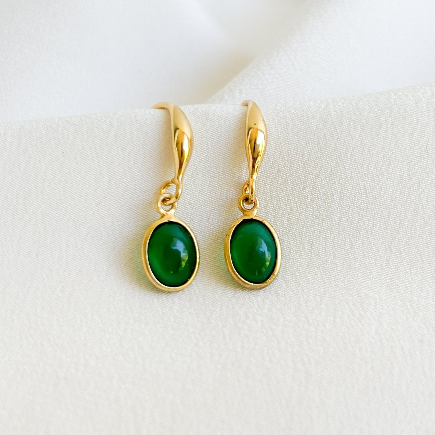 a pair of bezel gemstone earrings in 14K gold filled. Bezel set oval green onyx gemstones dangle from thick gold hook ear wires.