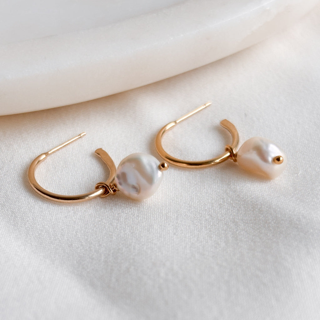 14k gold filled open hoop stud earrings with keshi pearl drops on a white fabric background