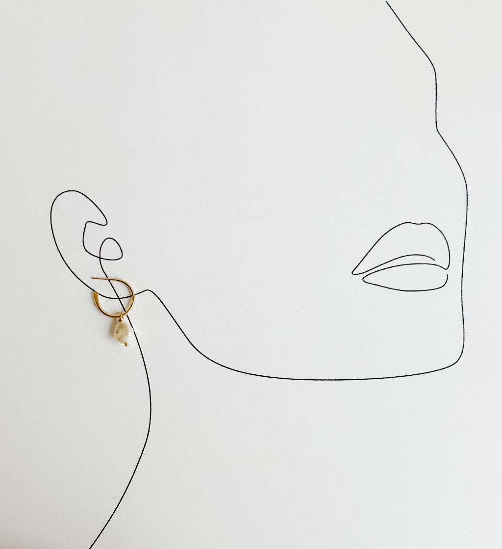 Minimalist line drawing of a face with an open hoop pearl drop stud earring on a light gray background