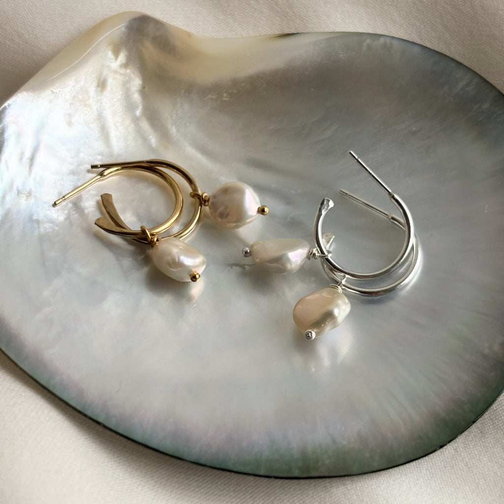 Two pairs of earrings on a large shell. The 3/4 hoop stud earrings feature keshi pearl drops that are removeable.