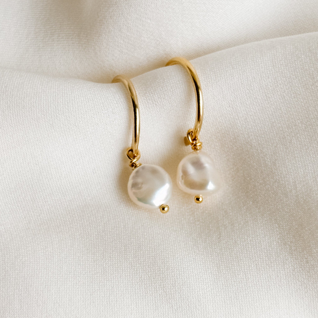 Gold 3/4 hoop stud earrings with pearl drops on a white fabric background
