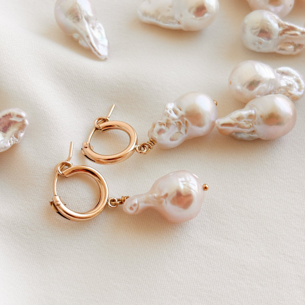 14k gold filled hoop earrings featuring large baroque fireball pearl drops are shown on a light background with loose pearls nearby.