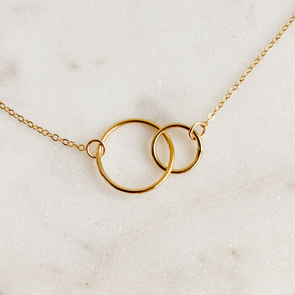 Gold necklace with interlocking rings on a light beige background