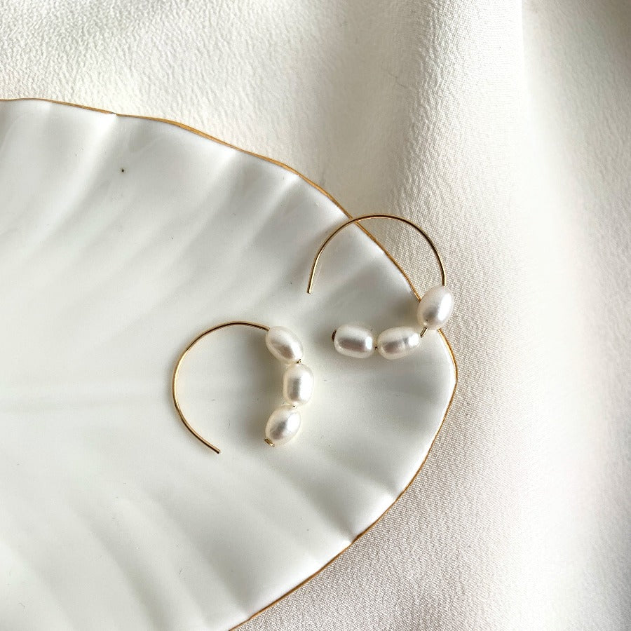 three oval freshwater pearls are set in dainty 14 karat gold filled circle earrings.