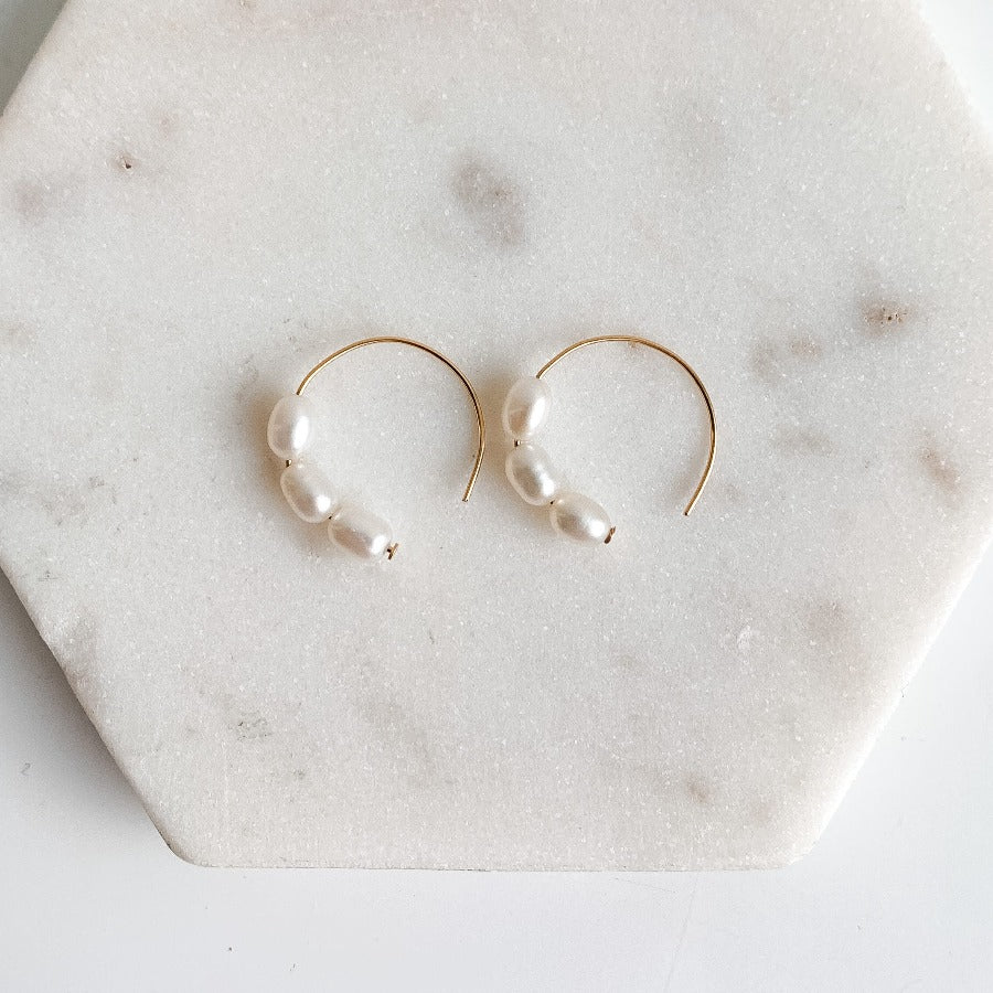 Three small oval freshwater pearls set in dainty 14k yellow gold filled circle earrings.