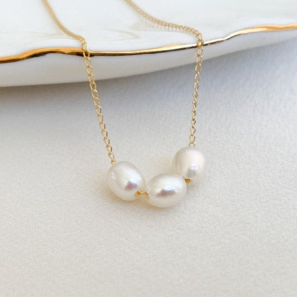 dainty freshwater pearls necklace featuring three high luster oval pearls strung on simple gold chain.