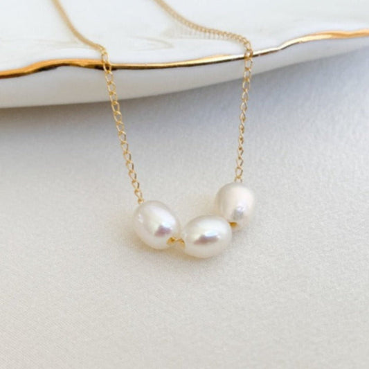 dainty freshwater pearls necklace featuring three high luster oval pearls strung on simple gold chain.
