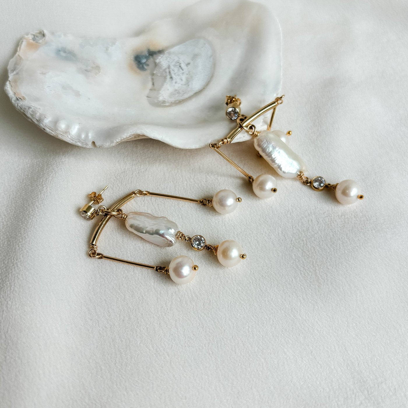 chandelier earrings in 14k gold filled. Earrings feature a large organic biwa pearl with three round dangling pearls and cubic zirconia accent that dangle from cubic zirconia stud earrings.