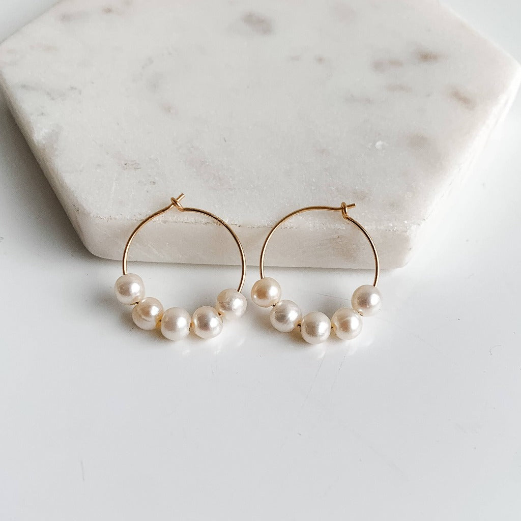 gold pearl hoop earrings featuring 5 freshwater pearls threaded on wire frames.