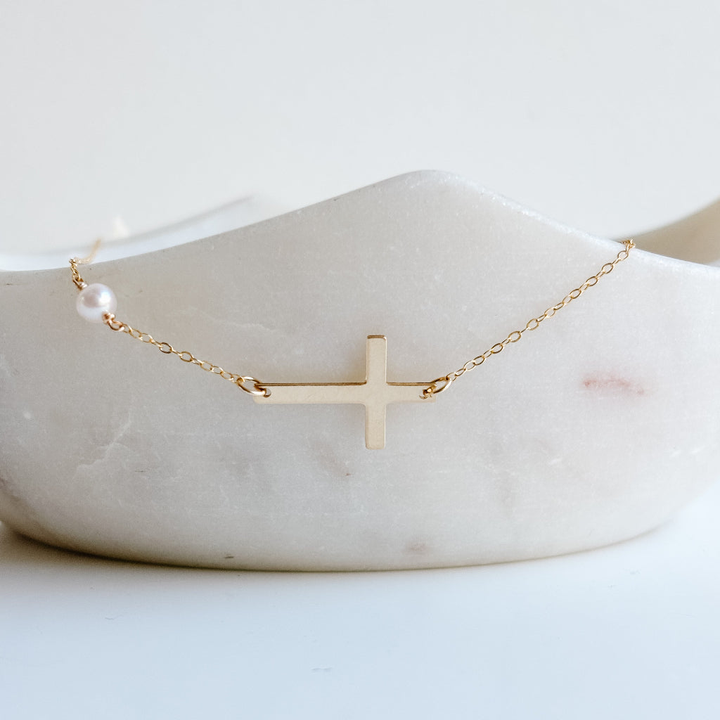 Gold cross necklace on a marble surface
