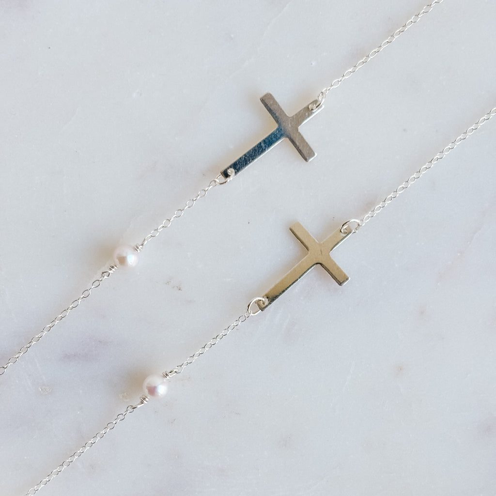 Silver necklaces with cross pendants on a marble surface