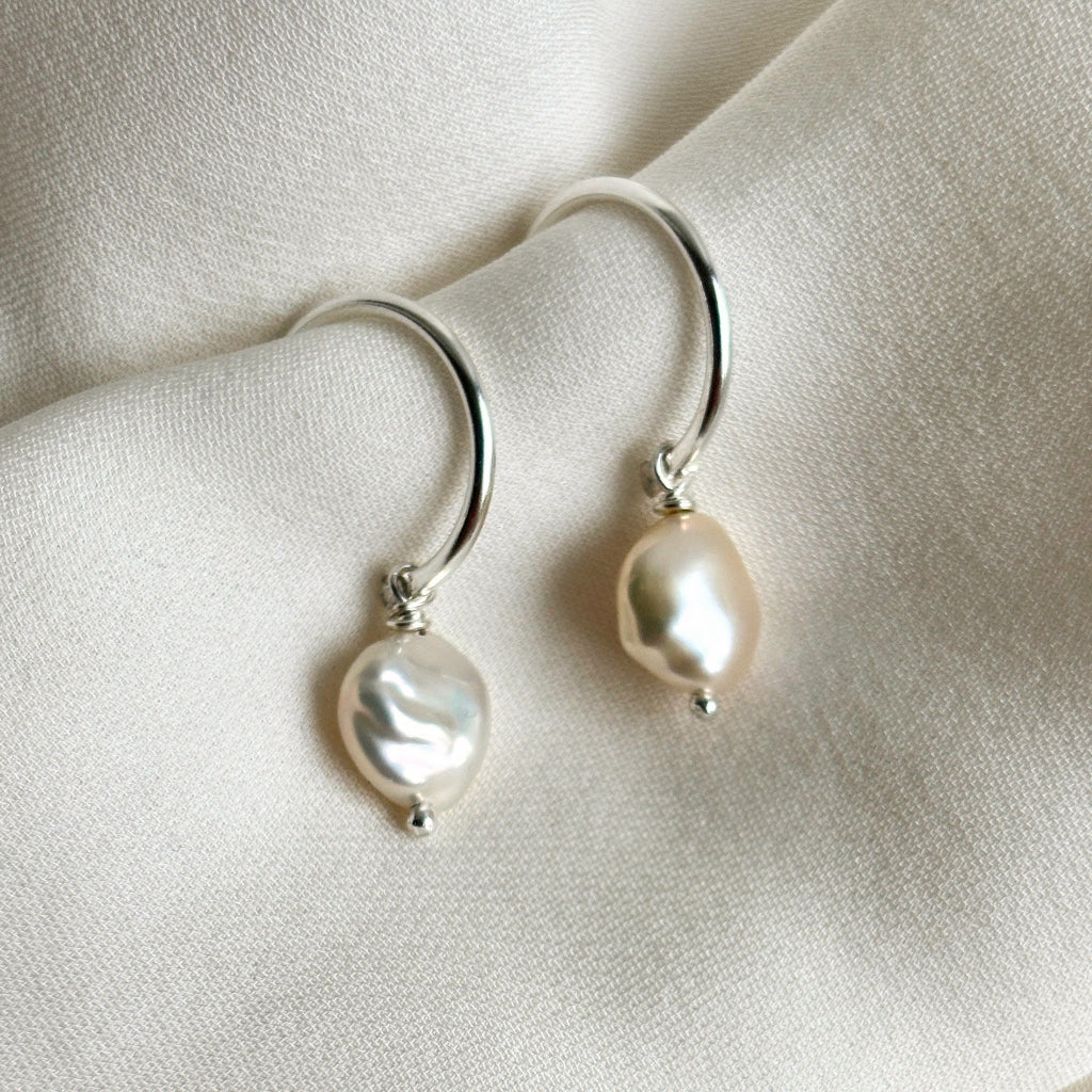 sterling silver open hoop stud pearl drop earrings on a soft beige fabric background