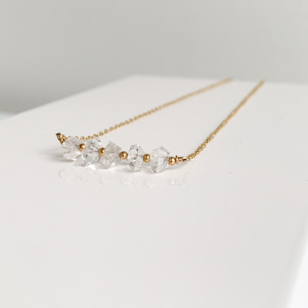 a dainty 14k gold filled necklace showcasing a row of herkimer diamond crystals alternating with tiny gold beads set in delicate chain.  