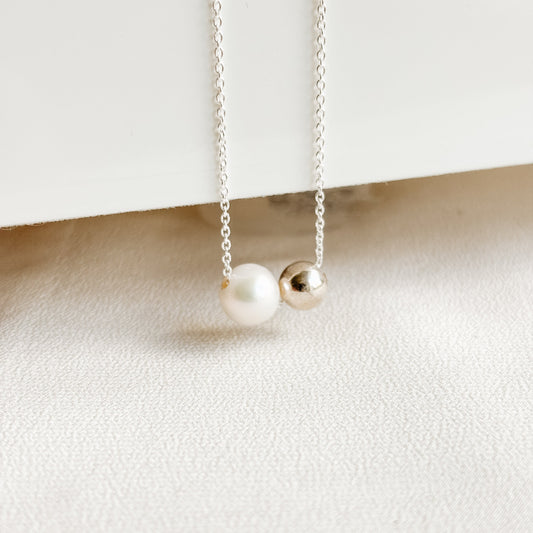 Necklace with a freshwater pearl and a sterling silver ball bead on a white background