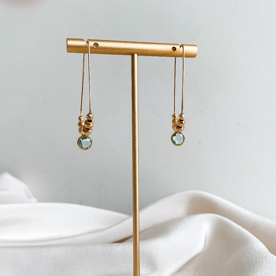 long gold dangle earrings featuring aqua gemstone charms and gold bead accents.