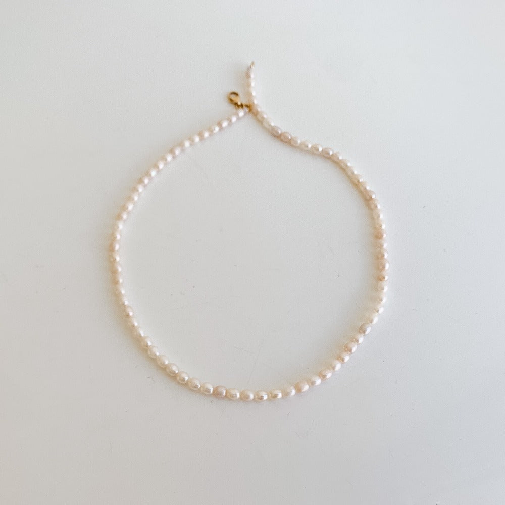 a dainty freshwater pearl strand choker necklace featuring petite oval-shaped freshwater pearls.