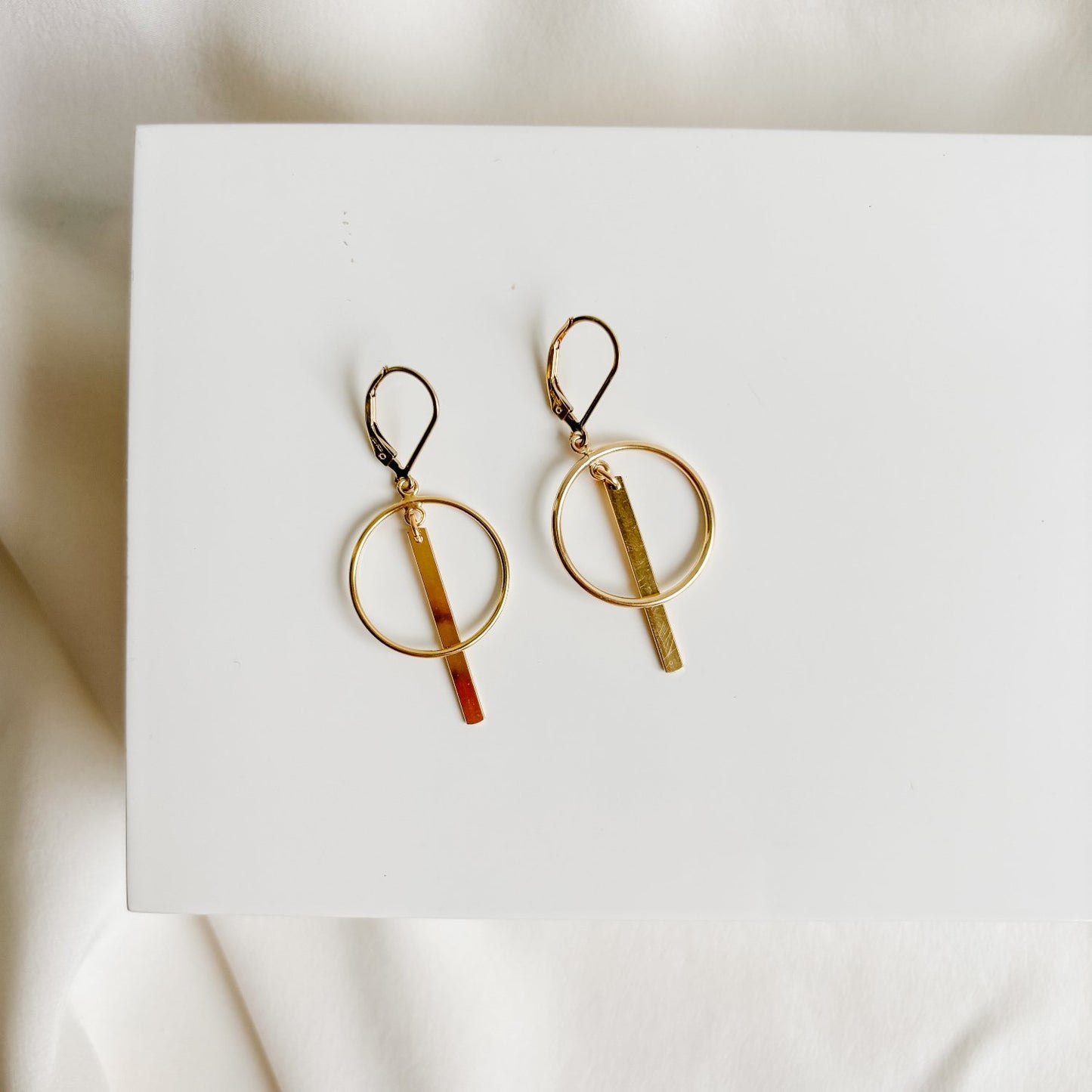 14k gold filled lever back earrings that feature open circles and linear gold bars that dangle from the ear wires. 