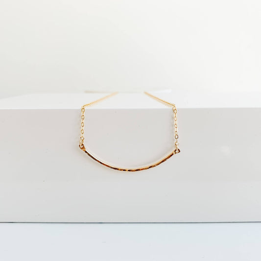 dainty 14k gold filled necklace featuring a textured curved bar pendant set into delicate chain.