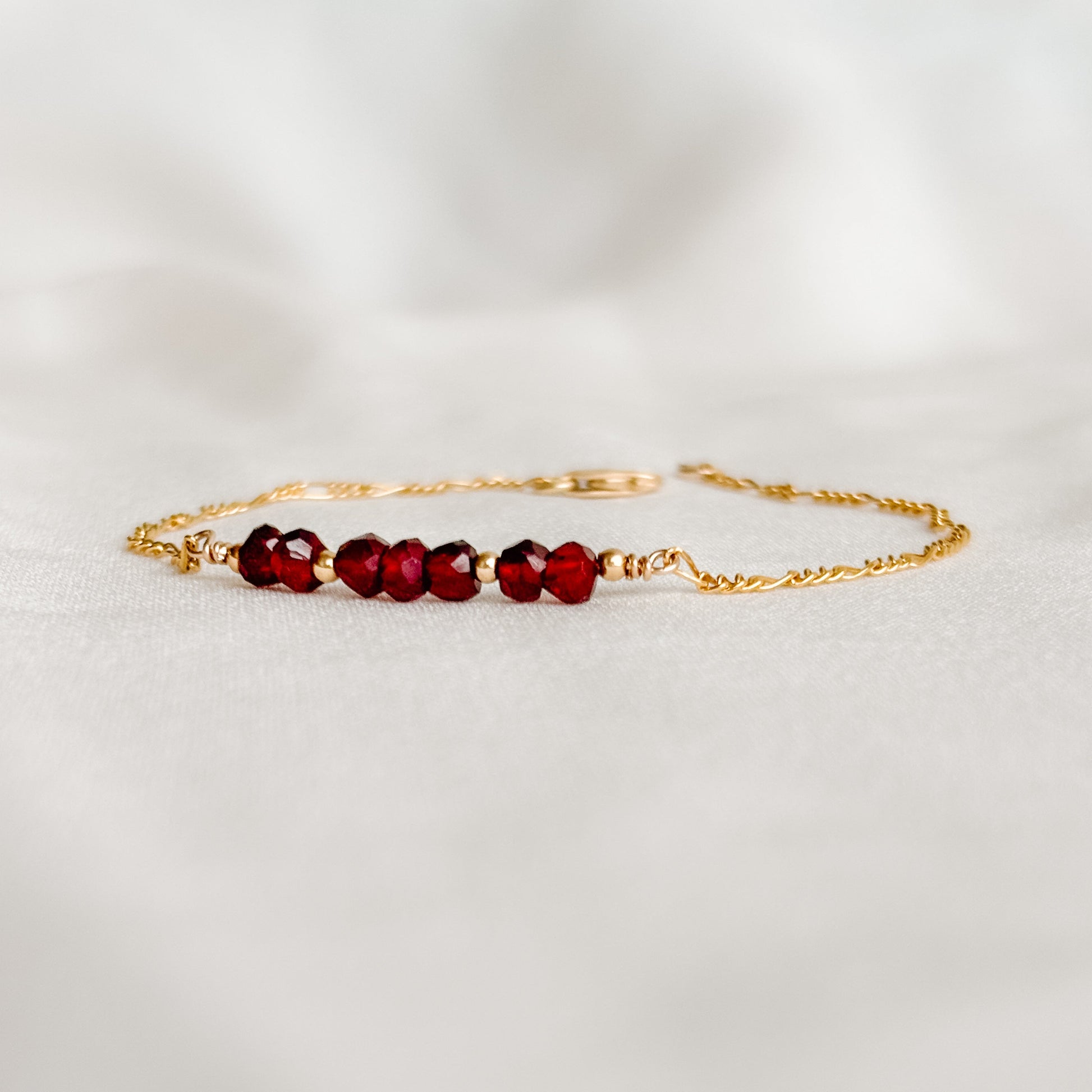 a dainty gemstone bar bracelet in 14k gold filled.  The five faceted round gemstones are accented with tiny gold ball beads and set into the Figaro chain.  