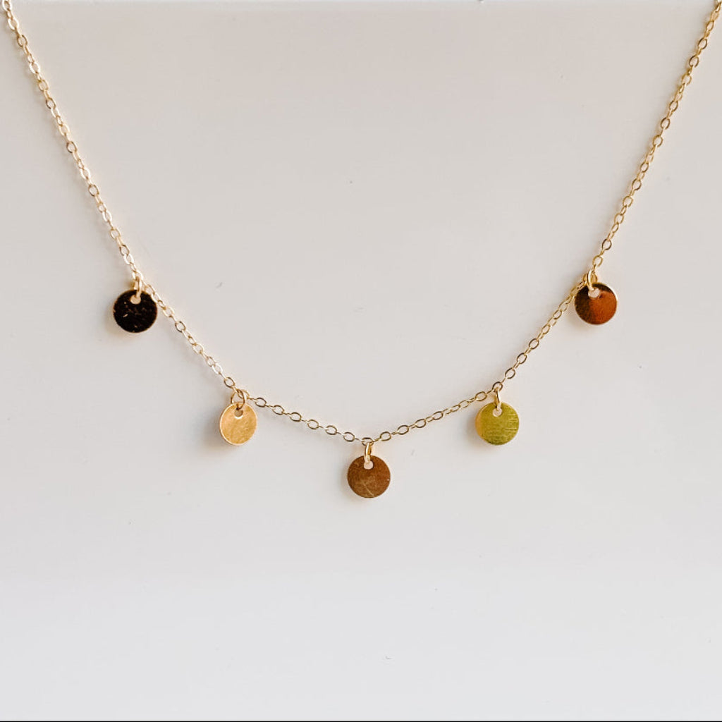 Gold necklace with 5 small round pendants on a light gray background - 14k gold filled.