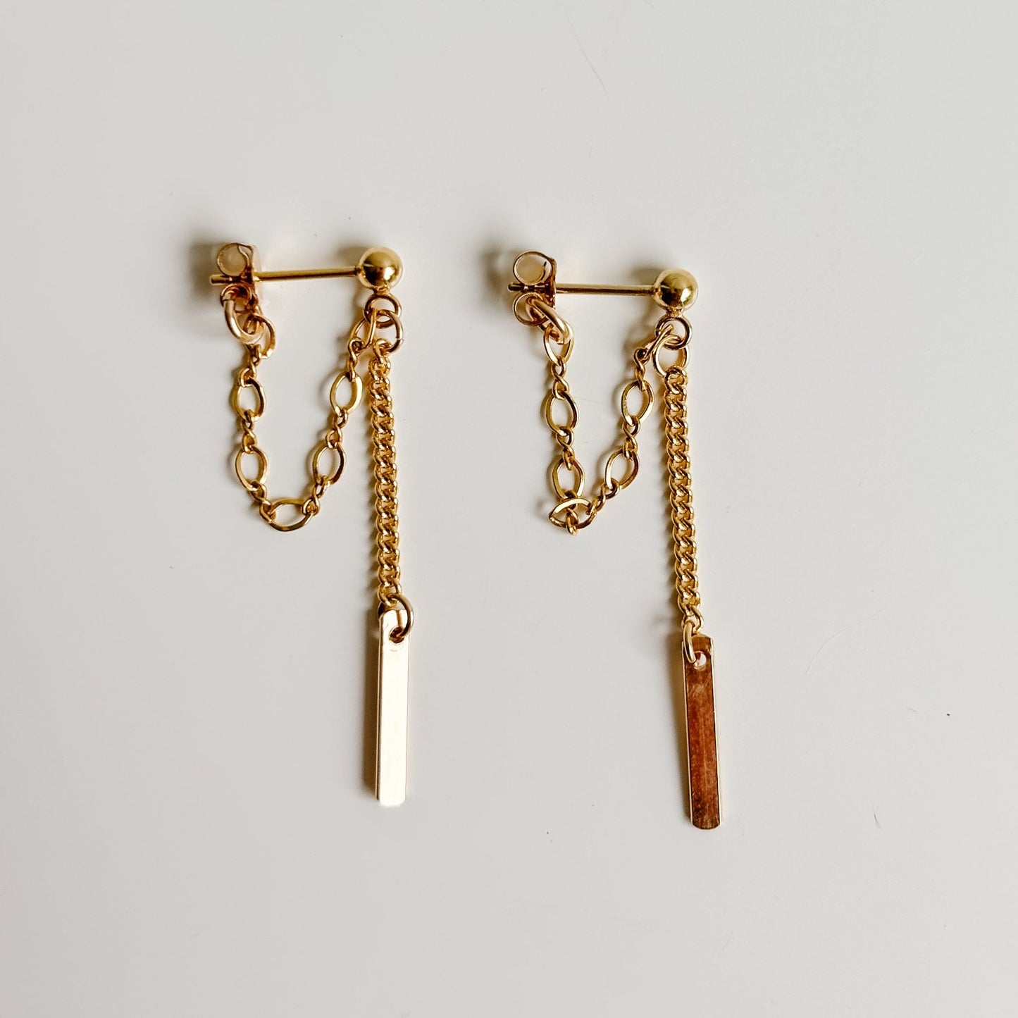 gold sphere post earrings in 14k gold filled that feature a loop of Figaro chain and a length of curb chain that ends in a petite rectangle tag charm.  