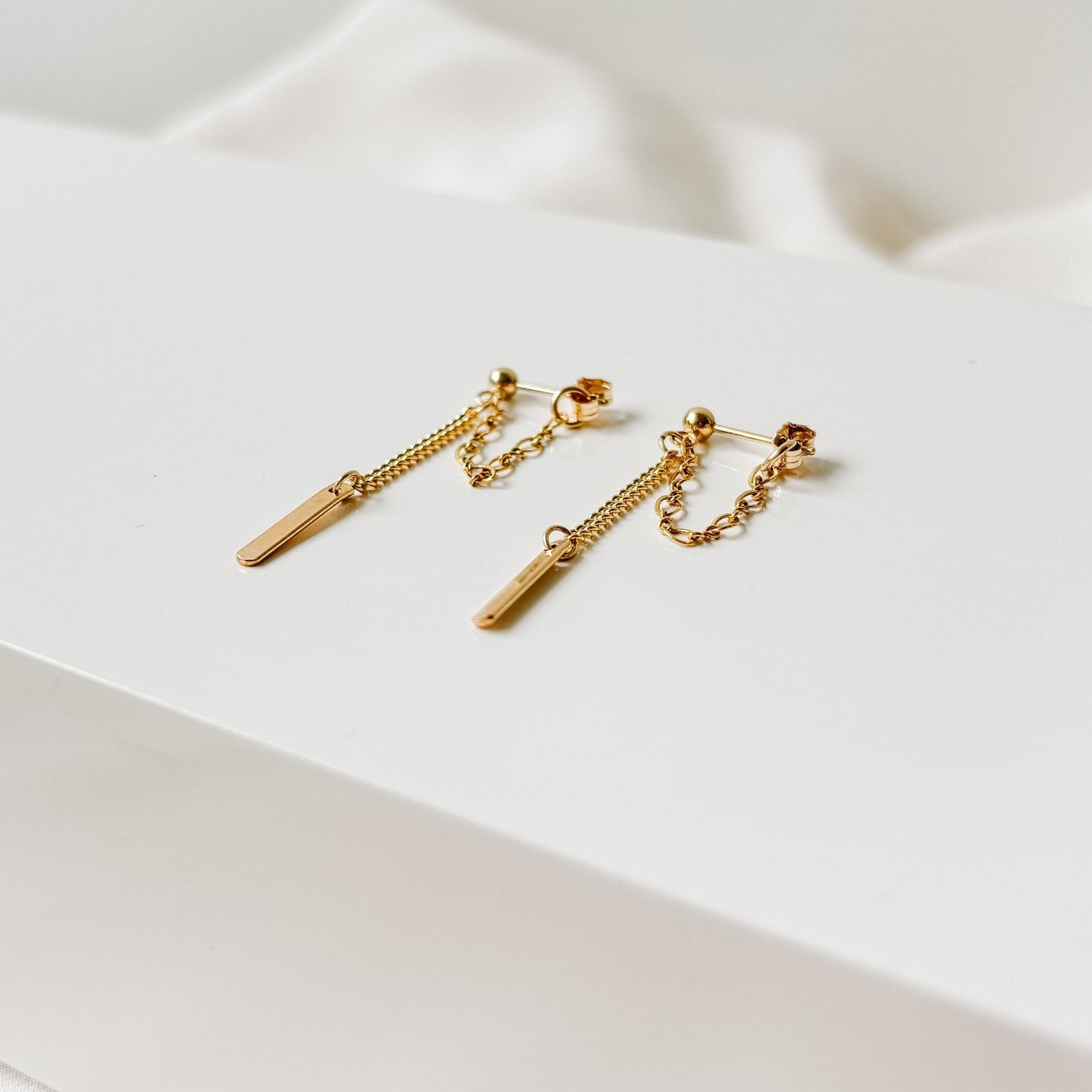 a pair of 14k gold filled mixed chain earrings in front back design.  Figaro chain forms a loop and curb chain drops from a gold sphere post.  The curb chain ends with a petite rectangle tag.   