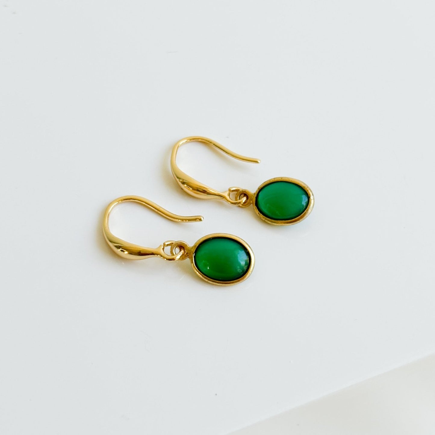 a pair of 14k gold filled hook earrings that feature oval shaped green onyx gemstone charms that are bezel set. 