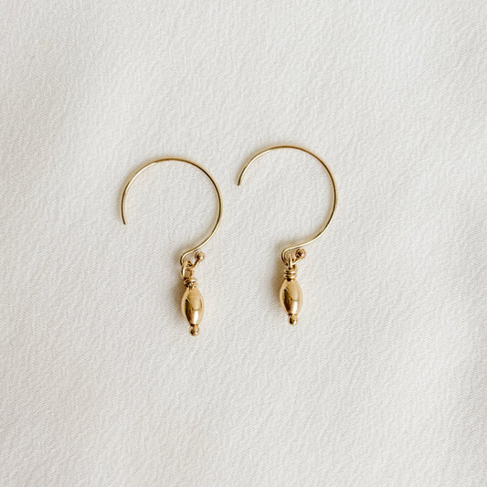 circle hook earrings in 14k gold filled that feature a petite dangling oval shaped gold bead.