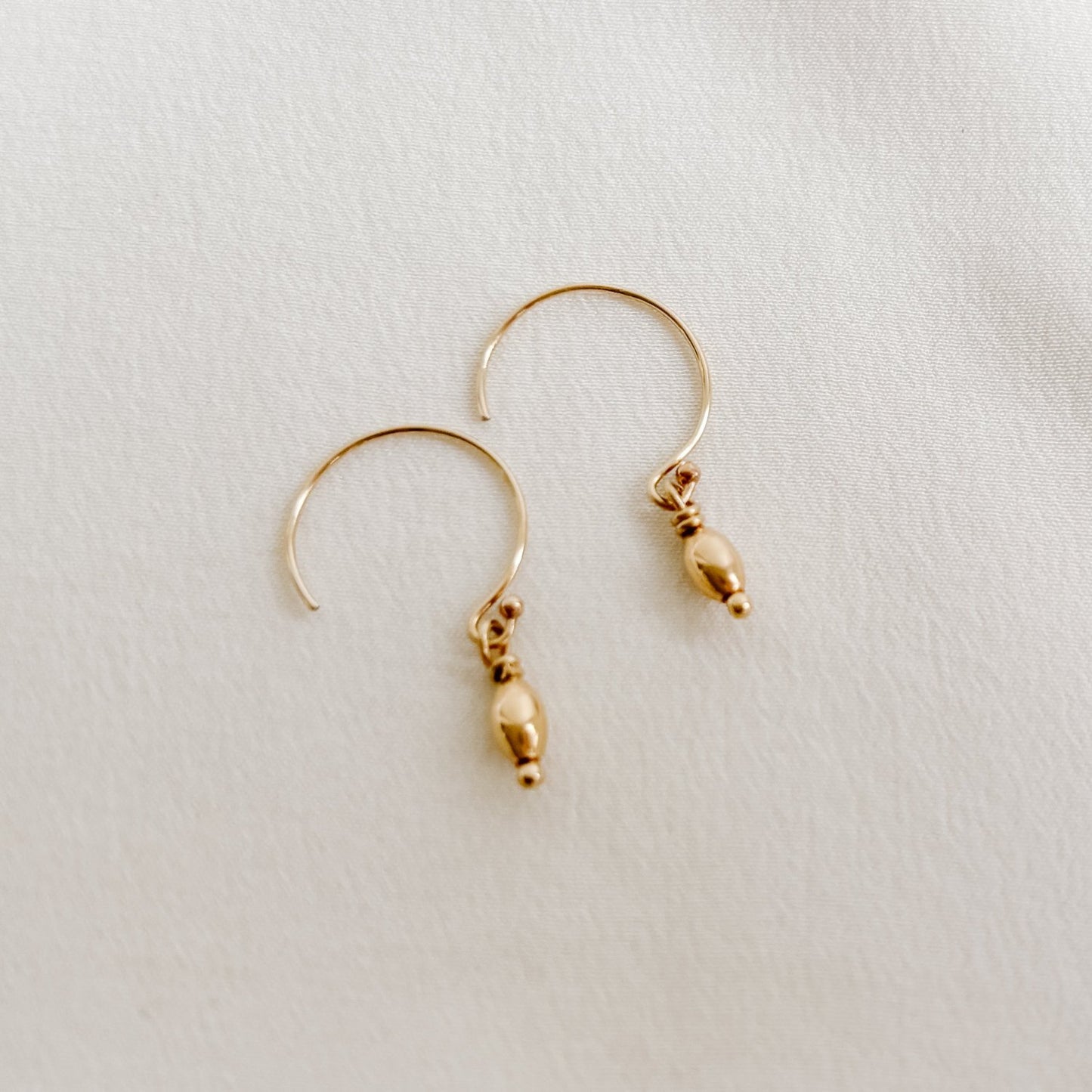 gold circle ear wire earrings with mini oval shaped gold bead charms.