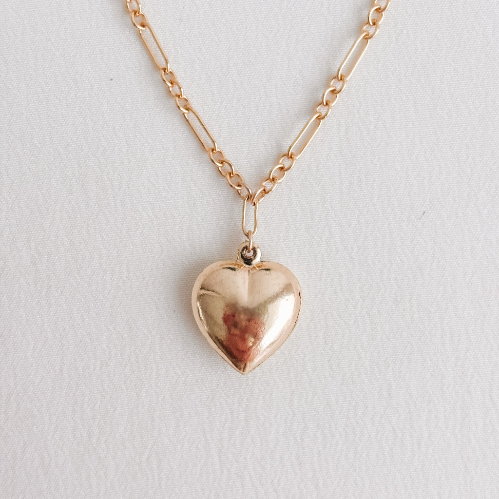 a 14k gold-filled long and short chain necklace that features a large puffy heart pendant