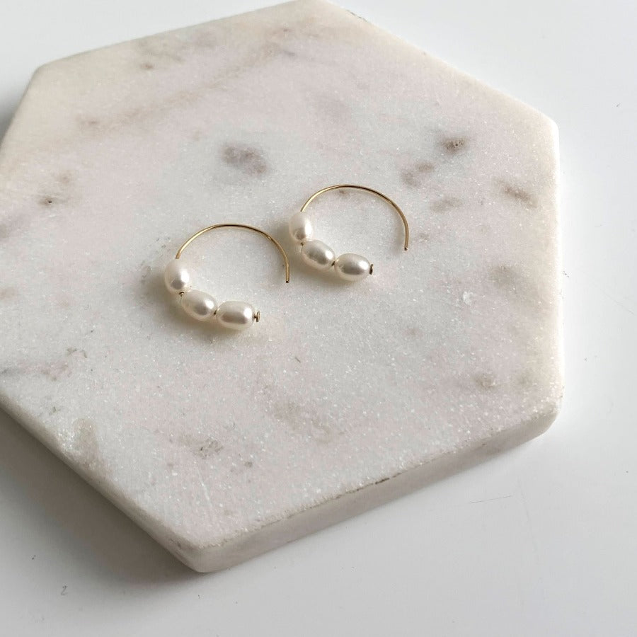 a pair of simple circle earrings threaded with three petite oval pearls.  