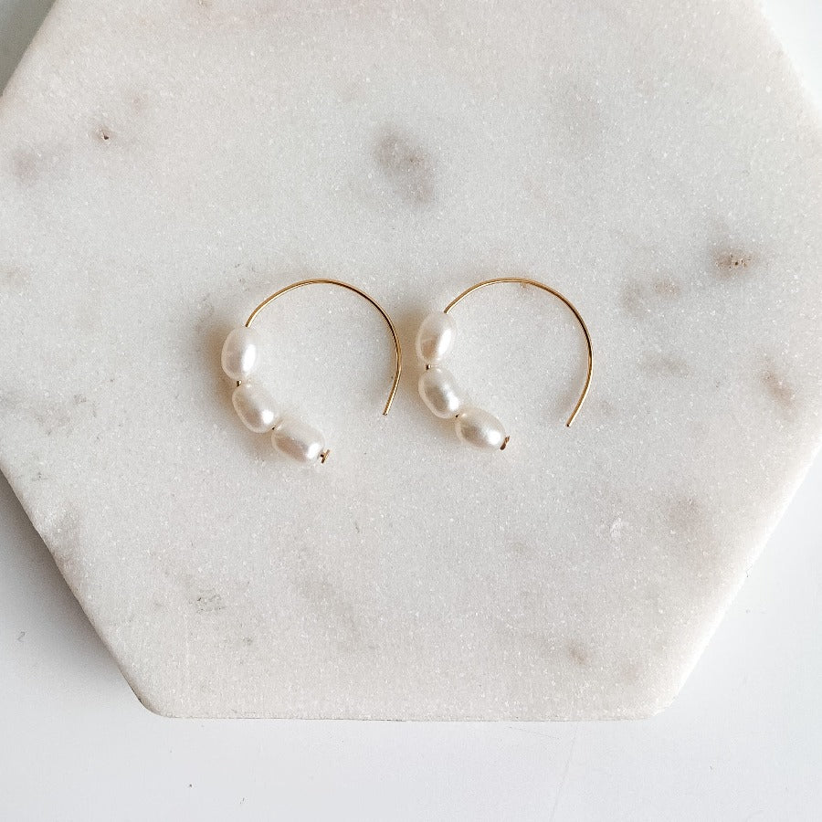 Three small oval freshwater pearls set in dainty 14k yellow gold filled circle earrings.  