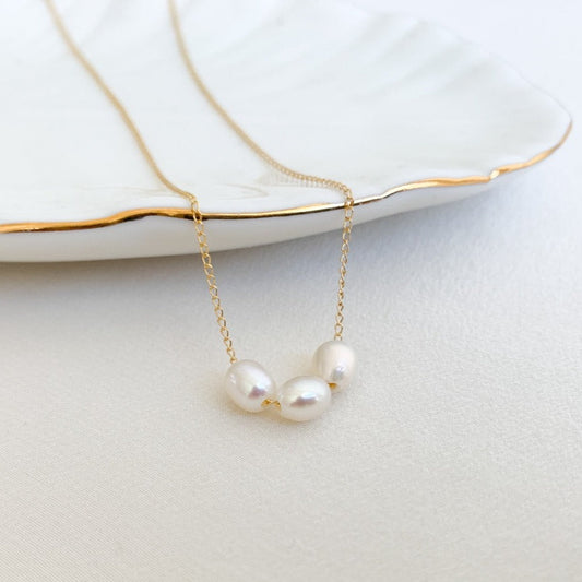 dainty freshwater pearls necklace featuring three high luster oval pearls strung on simple gold chain. 