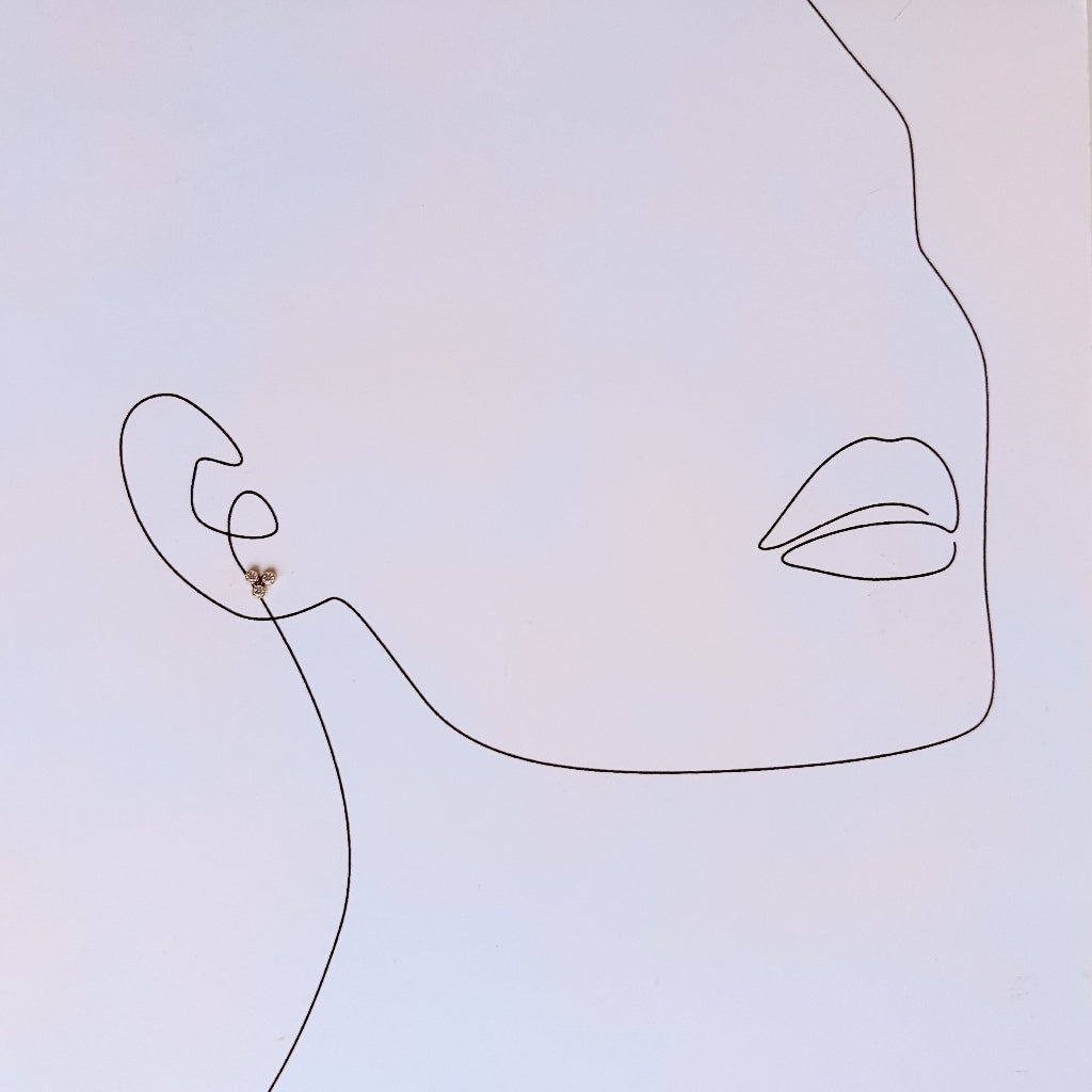 Minimalist line art of a face with a triple cz cluster stud earring on a light gradient background
