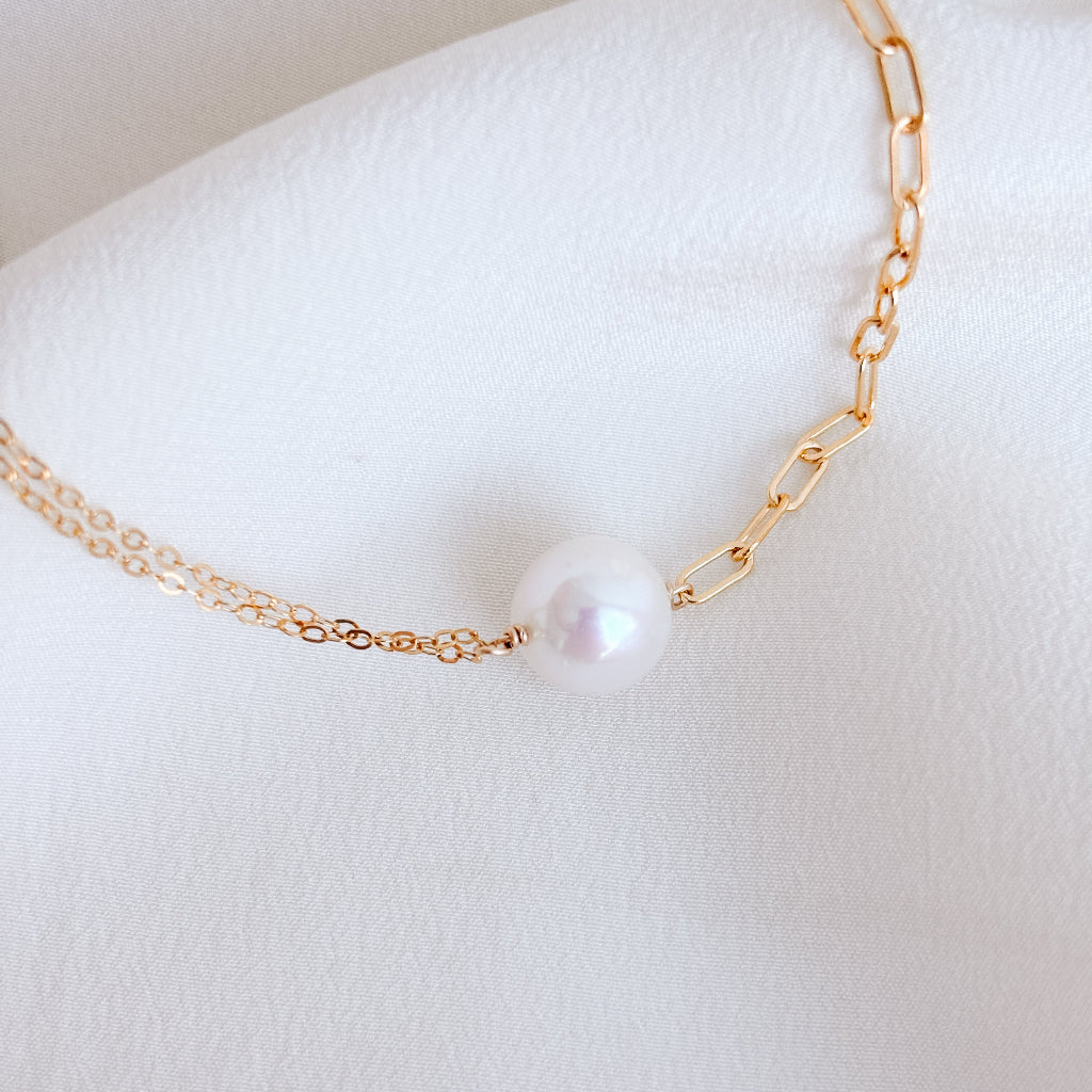 a pearl pendant necklace featuring two chain links on either side of a large Edison pearl - one side flat cable links and the other paperclip links