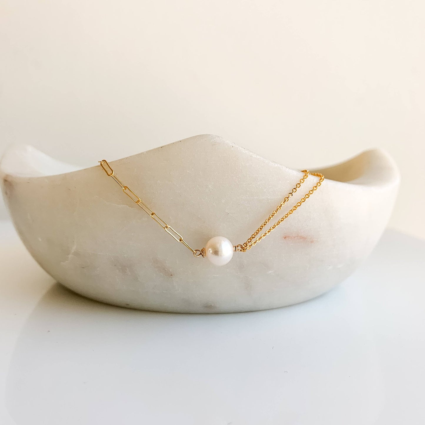 a pearl necklace featuring a pearl set in half paperclip chain and half double layer of cable chain necklace. 