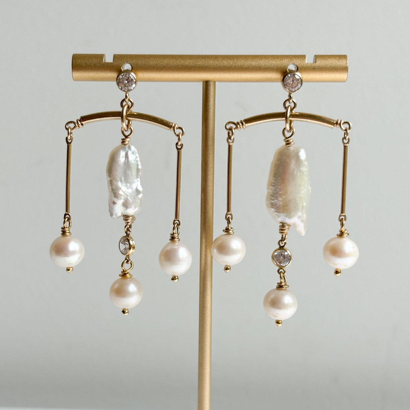 a pair of gold filled chandelier earrings that feature a large free shape pearl and 3 round pearls accented with cubic zirconia in a chandelier design.