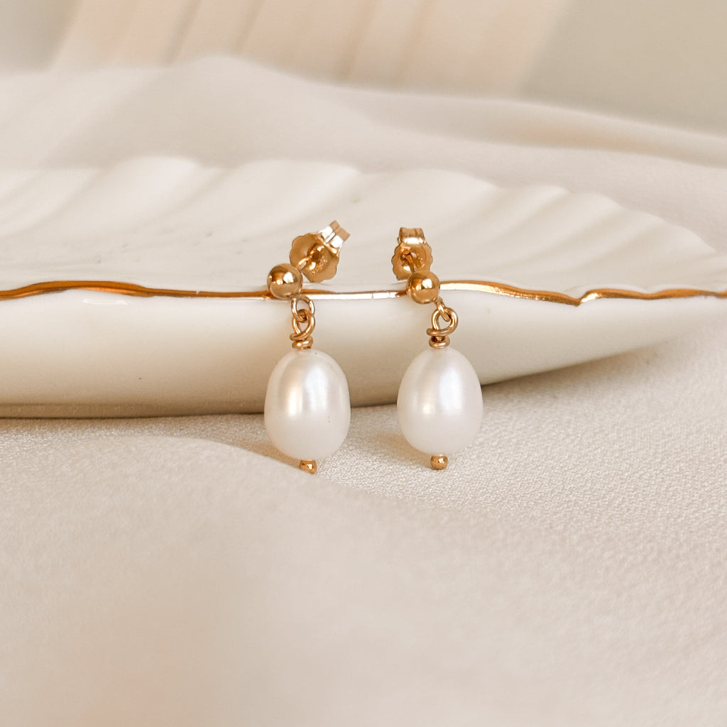 oval shaped pearls with 14k gold filled ball posts on a beige surface.