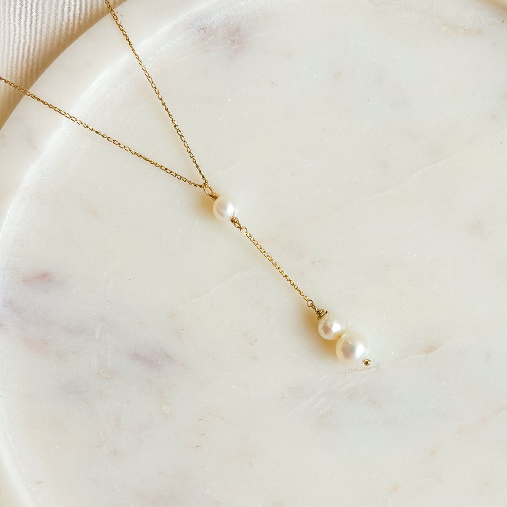 Gold necklace with pearls on a marble surface